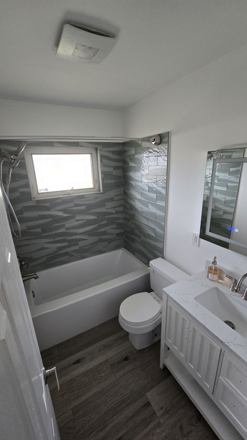 Hall bathroom with new tub, sage wave-pattern tile and white vanity