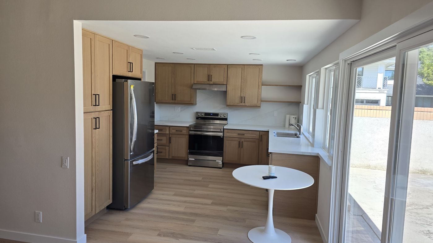 Remodeled kitchen with oak shaker cabinets, white quartz counters and full-height slab backsplash