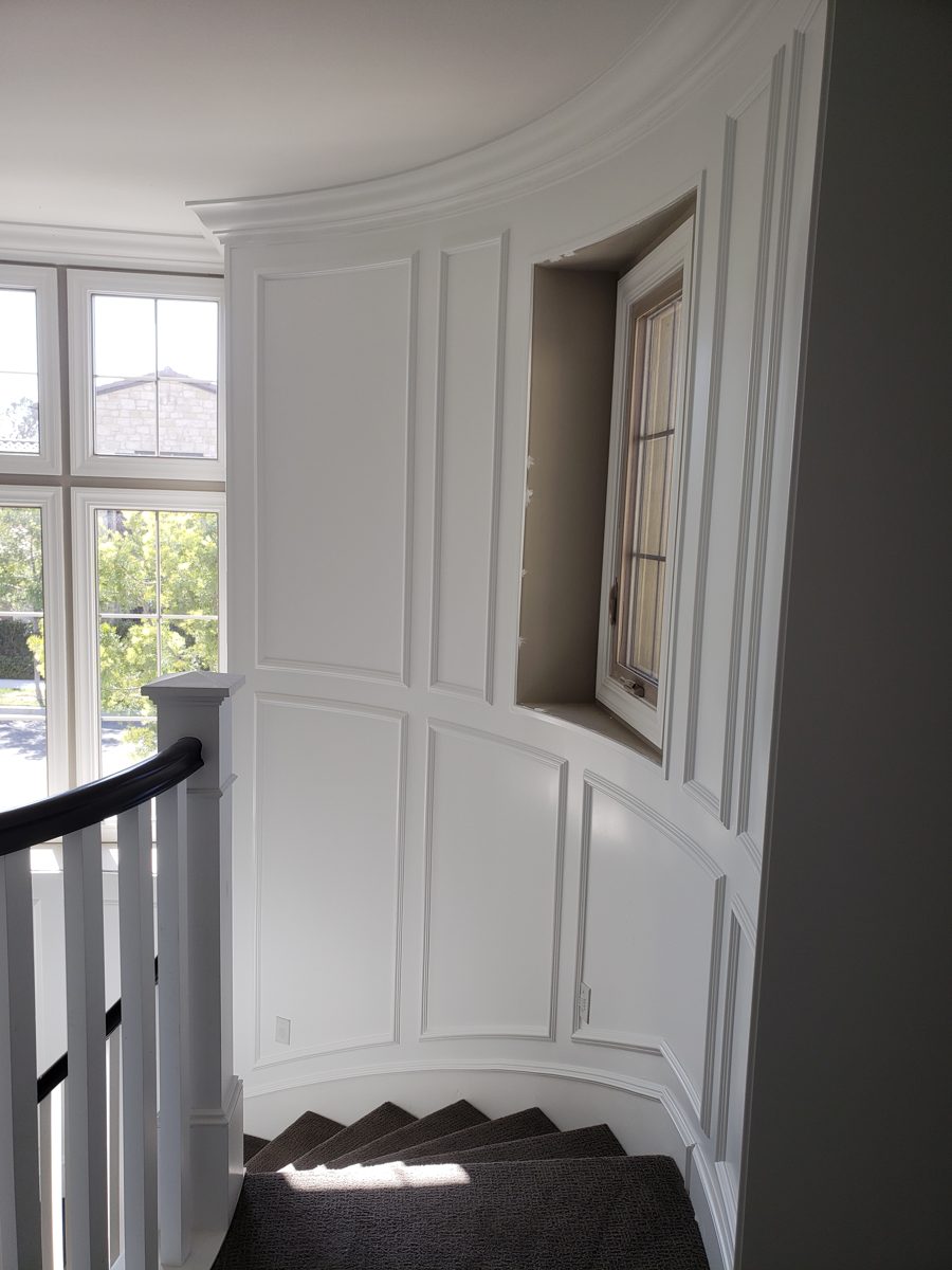 Curved wall with custom picture-frame panel molding and crown molding along the staircase